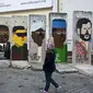 Seorang gadis melihat-lihat bekas Tembok Berlin yang digambari dengan karikatur para pemimpin dunia. Graffiti itu dilukis oleh artis Prancis Guillaume Kashima, dekat Checkpoint Charlie di Berlin, Jerman, 13 Januari 2013. (John MacDougall/AFP)