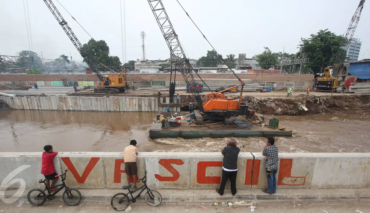 Warga mengamati pengerjaan proyek normalisasi Sungai Ciliwung di Jakarta, Selasa (8/11). Pemprov DKI menargetkan normalisasi Sungai Ciliwung rampung pada 2018 mendatang yang akan ditunjang dengan ketersediaan rusun. (Liputan6.com/Immanuel Antonius)