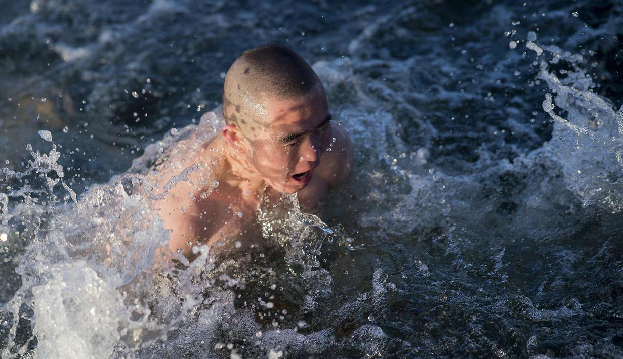 Seorang pria berenang di danau Hou Hai yang membbeku di Beijing, China (24/1). (AFP Photo/Nicolas Asfouri)