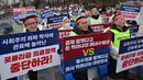 Para dokter memegang plakat bertuliskan "Hentikan Kebijakan Medis Populis!" dalam unjuk rasa memprotes rencana pemerintah menaikkan kuota pendaftaran tahunan di sekolah kedokteran, di dekat kantor kepresidenan di Seoul pada tanggal 21 Februari 2024. (Jung Yeon-je/AFP)