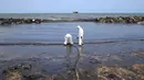 Penjaga pantai Sri Lanka membersihkan tumpahan minyak di sebuah pantai di Uswetakeiyawa, Kolombo, Senin (10/9). Tumpahan minyak mencemari hamparan pantai sekitar 2 kilometer.  (AP Photo/Eranga Jayawardena)