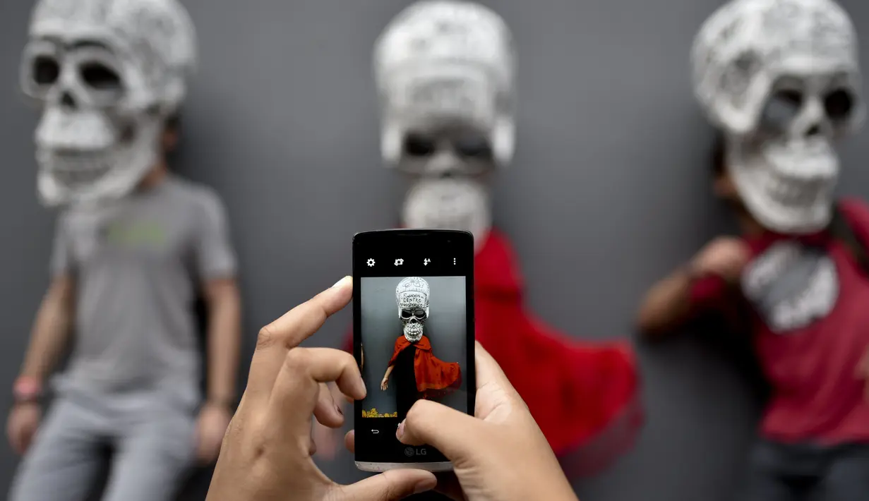 Sejumlah orang berfoto dengan replika tengkorak saat pameran dan kontes di perayaan Hari Kematian di Mexico City (1/11). Perayaan ini menandai bulan kesembilan dari kalender matahari suku Aztec. (AFP Photo/Yuri Cortez)
