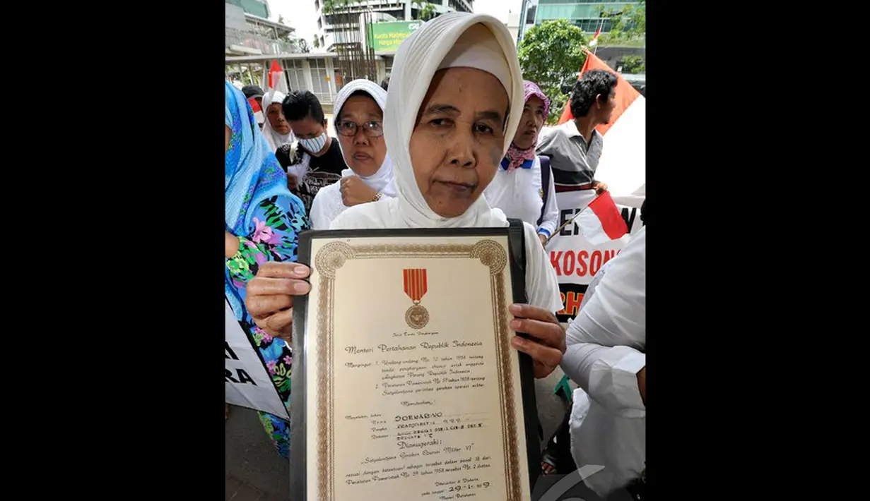 Salah satu keluarga veteran  membawa piagam bintang gerilya saat melakukan unjuk rasa di depan Gedung KPK, Jakarta, Kamis (18/12/2014). (Liputan6.com/Miftahul Hayat)