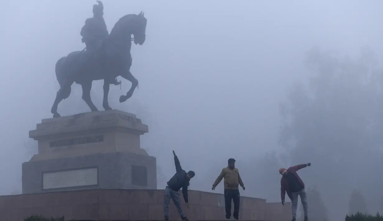 Orang-orang melakukan pemanasan saat berolahraga di tengah kabut tebal selama hari yang dingin di sebuah taman di Amritsar, India (30/12/2019). Di banyak kota di India Utara, termasuk ibu kota, New Delhi, jarak pandang menyusut hingga 200 meter, menurut Badan Meterologi India. (AFP/Narinder Nanu)