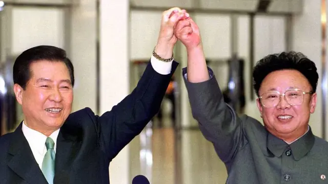 Presiden Korea Selatan, Kim Dae-jung dan pemimpin Korut Kim Jong-il berpegangan tangan sebelum menandatangani perjanjian di tengah pertemuan bersejarah antara dua Korea di Pyongyang pada 14 Juni 2000.