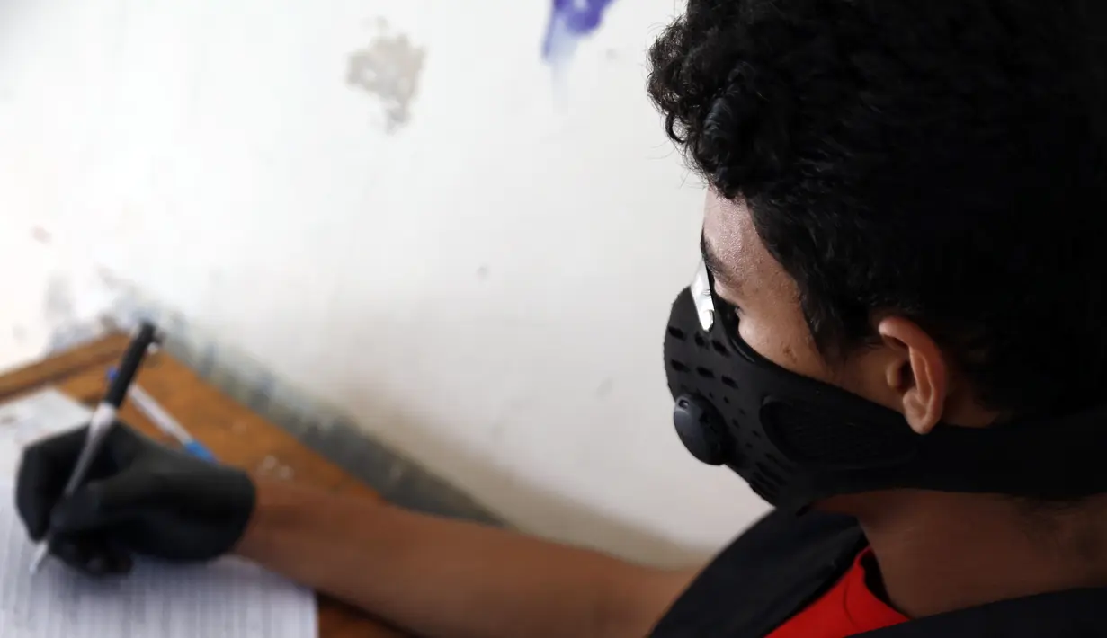 Seorang siswa yang mengenakan masker mengikuti ujian di sebuah sekolah di Sanaa, Yaman (30/8/2020). (Xinhua/Mohammed Mohammed)
