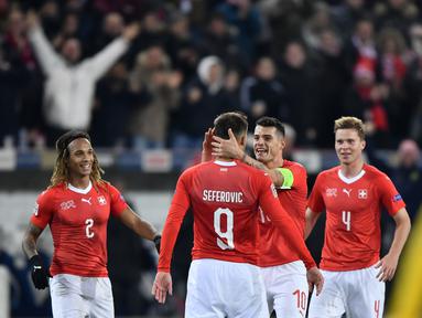Haris Saferovic dan Granit Xhaka merayakan gol pertama timnas Swiss pada laga Nations League yang berlangsung di stadion Swiss porarena, Senin (19/11). Timnas Swiss menang 5-2. (AFP/Fabrice Coffrini)