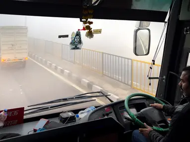 Seorang pengemudi bus mengemudi di tengah kabut asap pagi dekat Lucknow, India, Selasa (20/12/2022). India Utara mengalami kabut pertama musim ini dan diperkirakan akan berlangsung selama lima hari ke depan yang mengganggu transportasi kereta api, jalan raya, dan udara. (AP Photo/Rajesh Kumar Singh)