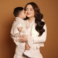 Bersama si kecil, Nathalie Holscher tampil smart casual mengenakan pakain serba putih, dengan crop top jaket, inner lengan panjang, dan skirt nya. (@nathalieholscher)