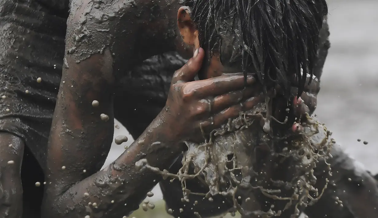 Seorang anak mencuci mukanya saat bermain permainan Kabaddi di sebuah lahan yang digenangi air di Kolkata (8/9/2019). Olahraga ini merupakan olahraga nasional Bangladesh, dan olahraga negara bagian Punjab, Tamil Nadu dan Andhra Pradesh di India. (AFP Photo/Dibyangshu Sarkar)