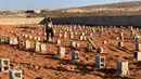 Seorang pria berjalan melewati makam korban banjir bandang di Derna, Libya, Jumat (15/9/2023). Jumlah korban tewas di kota pesisir Derna telah melonjak hingga lebih dari 10 ribu orang ketika upaya pencarian terus dilakukan menyusul banjir besar yang diakibatkan oleh jebolnya dua bendungan saat hujan lebat, kata Bulan Sabit Merah Libya pada Kamis. (AP Photo/Yousef Murad)