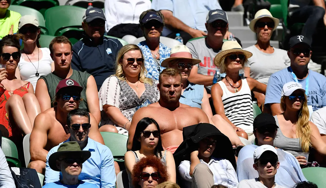 Sejumlah pria membuka bajunya saat menyaksikan pertandingan putaran tunggal putra antara petenis Bulgaria Grigor Dimitrov dan petenis Austria Dennis Novak pada hari pertama turnamen tenis Australia Terbuka di Melbourne (15/1). (AFP Photo/Greg Wood)