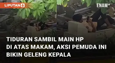 Aksi seorang pemuda tiduran sambil bermain hp di atas makam mengundang perhatian