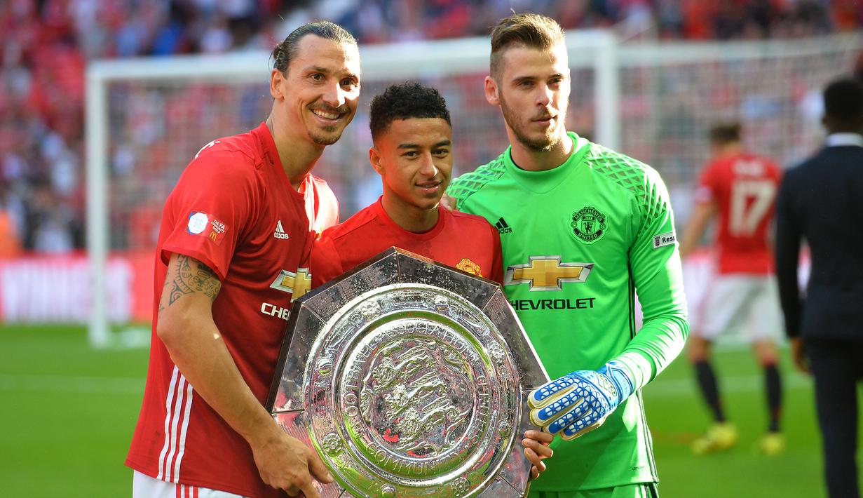 Kiper Manchester United, David de Gea (kanan), Jesse Lingard (tengah), dan Zlatan Ibrahimovic berfoto bersama dengan trofi Community Shield setelah memenangkan laga saat melawan Leicester City di Stadion Wembley, London, 7 Augustus 2016. Kiper berkebangsaan Spanyol tersebut berhasil mempersembahkan tiga trofi Community Shield saat membela Setan Merah, yaitu pada 2011, 2013, dan 2016. (AFP/Glyn Kirk)
