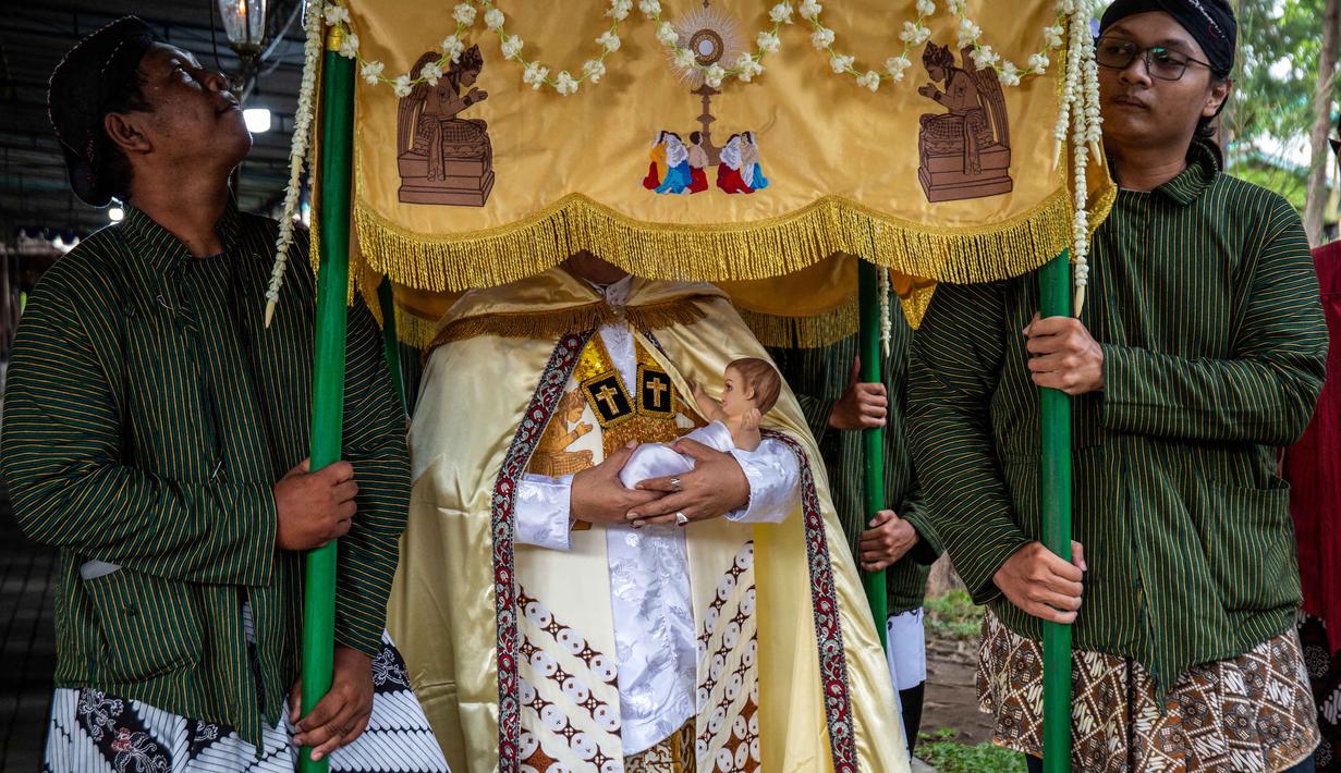Gereja Hati Kudus Yesus ini dikenal memiliki ciri khas yakni memadukan unsur budaya lokal dalam setiap perayaan keagamaan. Tampak dalam foto, umat Katolik membawa patung bayi Yesus sambil menunggu Misa Malam Natal di Gereja Hati Kudus Yesus di Ganjuran, Bantul, Yogyakarta, pada Rabu 24 Desember 2025. (DEVI RAHMAN/AFP)