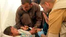 Seorang pria menghibur putrinya saat menerima perawatan dari dokter akibat keracunan makanan di Sebuah tenda medis di kamp Hassan Sham U2, Irak (13/6). Ratusan pengungsi keracunan makanan usai menyantap makanan buka puasa. (AP Photo/Balint Szlanko)