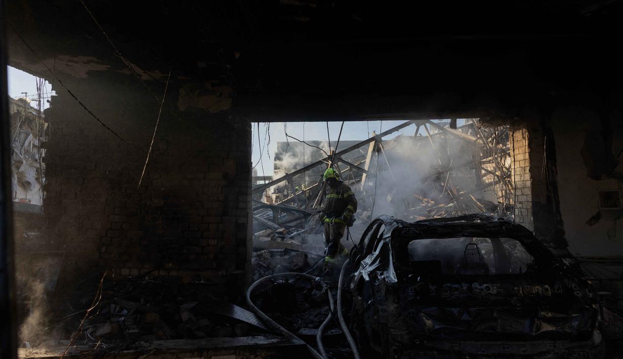 Seorang petugas pemadam kebakaran berjalan melewati dealer mobil yang rusak akibat serangan rudal dan drone besar-besaran Rusia di Kyiv pada Selasa 2 Juni 2026, di tengah invasi Rusia ke Ukraina. (Tetiana DZHAFAROVA/AFP)