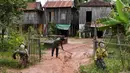 Dua orang-orangan sawah diikat ke pagar depan sebuah rumah di provinsi Kampong Cham, Kamboja, 11 Oktober 2020. Para petani di desa itu menggunakan orang-orangan sawah atau disebut juga Tim Mong untuk menangkal virus corona  Covid-19 berdasarkan kepercayaan yang mereka yakini. (TANG CHHIN Sothy/AFP)