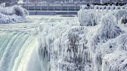 Pengunjung mengambil gambar Horseshoe Falls di Air Terjun Niagara yang membeku di Ontario, Kanada, Jumat (29/12). Cuaca dingin melanda sebagian besar wilayah utara Amerika Serikat di akhir tahun ini. (Aaron Lynett/Canadian Press via AP)