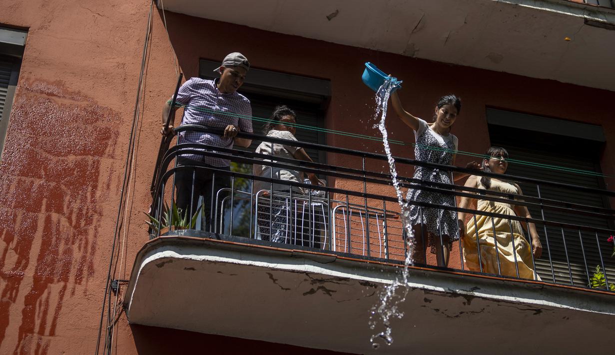 Orang-orang saling melempar air saat perang air tahunan di jalan-jalan lingkungan Vallecas, Madrid, Spanyol, 17 Juli 2022. Para tetangga yang berada di balkon mereka tak henti-hentinya melemparkan air untuk mengisi ember air orang-orang yang lewat. (AP Photo/Manu Fernandez)