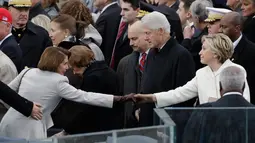 Mantan Menteri Luar Negeri AS, Hillary Clinton berjabat tangan dengan House Minority Leader, Nancy Pelosi usai upacara pelantikan Donald Trump menjadi Presiden AS ke-45 di Washington, DC, AS, (20/1). (Win McNamee/Pool Photo via AP)