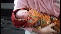 Bayi tampan saat digendong oleh istri dari salah, wrong tukang ojek yang menemukannya (Fauzan/Liputan6.com)