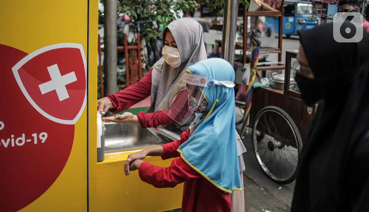 Pengunjung yang mengenakan masker mencuci tangan saat akan masuk Pasar Kebayoran Lama, Jakarta Selatan, Senin (22/6/2020). Pasar Kebayoran Lama menerapkan protokol kesehatan bagi pengunjung dan pedagang untuk mengantisipasi penularan COVID-19. (Liputan6.com/Faizal Fanani)