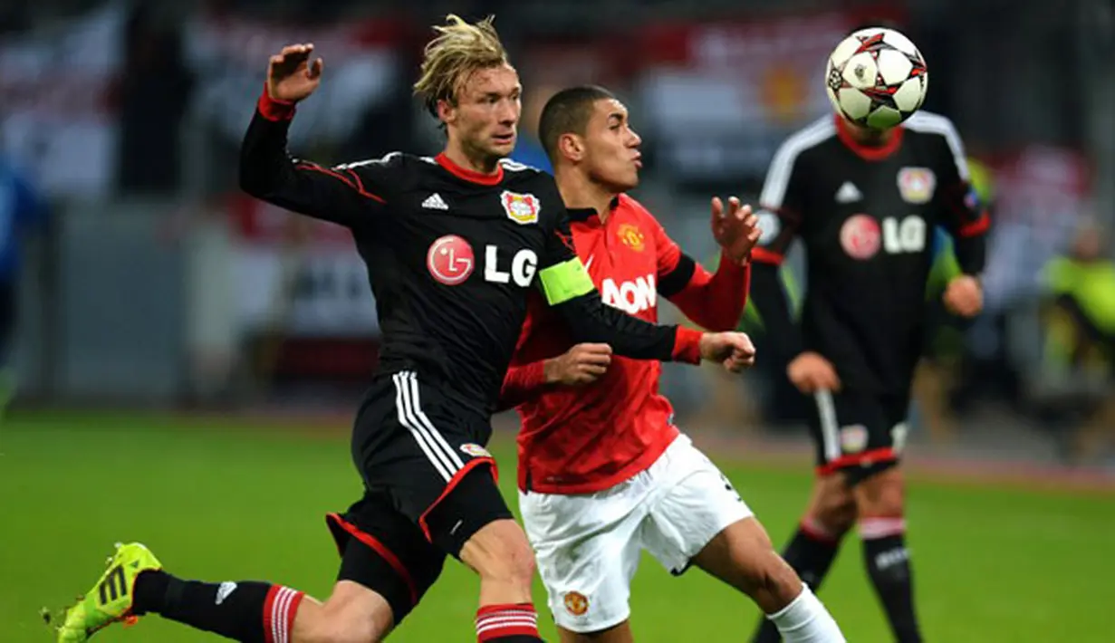 Gelandang Bayer Leverkusen Simon Rolfes (kiri) duel dengan bek Manchester United Chris Smalling pada pertandingan sepak  Liga Champions Grup A antara Bayern Leverkusen vs Manchester United di Leverkusen, Jerman Barat (281113). (AFP/Patrik Stollarz)