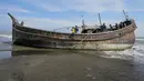 Penduduk desa melihat perahu kayu yang digunakan oleh orang-orang Rohingya di Pidie, provinsi Aceh pada 27 Desember 2022. Pengungsi Rohingya menerima perawatan medis darurat setelah sebuah kapal yang membawa hampir 200 orang mendarat di Indonesia pada 26 Desember, kata pihak berwenang, dalam pendaratan keempat di negara dalam beberapa bulan terakhir. (AFP/Amanda Jufrian)