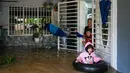Seorang perempuan dan anak-anaknya bersiap untuk mengungsi dari rumah mereka di daerah banjir di Yong Peng, negara bagian Johor Malaysia, Sabtu (4/3/2023). Banjir di Malaysia biasa terjadi selama musim hujan tahunan antara Oktober dan Maret, tetapi hujan deras minggu ini membuat banyak penduduk Johor berebut mencari tempat berlindung. (Photo by Mohd RASFAN / AFP)