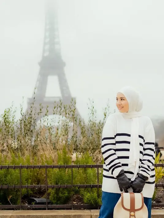 Tya Ariestya memilih keliling Eropa bersama suami dan anak-anaknya. Saat di Paris, ia mengenakan kerudung putih dipadukan sweater putih bergaris hitam serta rok denimnya. [@tya_ariestya]