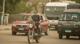 Seorang pria yang mengenakan masker mengendarai sepeda motor di sebuah jalan di Kairo, Mesir, pada 5 April 2020. Mesir pada Sabtu (4/4) melaporkan lima kematian baru akibat infeksi COVID-19, menjadikan total kasus kematian di negara tersebut mencapai 71. (Xinhua/Wu Huiwo)