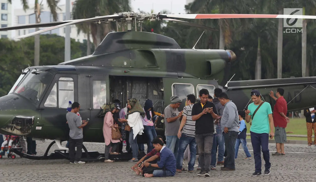 Warga mengerumuni helikopter TNI di kawasan Monumen Nasional, Jakarta, Jumat (19/4). Libur panjang perayaan Paskah 2019 dimanfaatkan warga untuk berwisata di kawasan Monumen Nasional. (Liputan6.com/Helmi Fithriansyah)