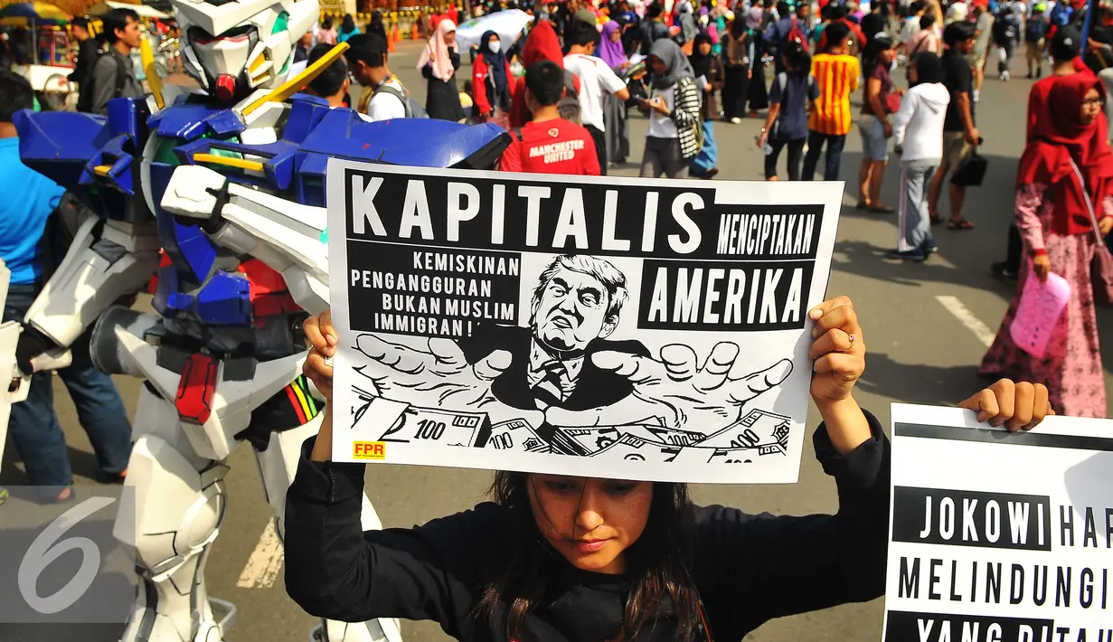 Seorang wanita menunjukan poster saat melakukan aksi terkait kebijakan Presiden Amerika Serikat Donald Trump di Jakarta, Minggu (5/2). (Liputan6.com/Angga Yuniar)