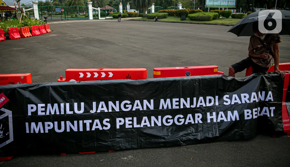 Poster bertuliskan "Pemilu Jangan Menjadi Sarana Impunitas pelanggaran HAM Berat" saat anggota Jaringan Solidaritas Korban untuk Keadilan (JSKK) melakukan Aksi Kamisan ke-795 di seberang Istana Merdeka, Jakarta, Kamis (16/11/2023). (Liputan6.com/Faizal Fanani)