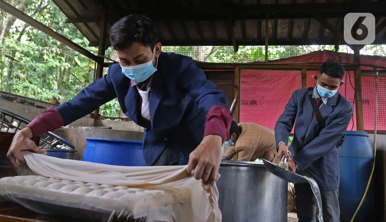 Pekerja memproduksi tahu dengan pakain seperti pekerja kantoran di daerah Sukaraja, Bogor, Senin (14/12/2020). Ide ini untuk membangkitkan semangat dan kepercayaan diri agar termotivasi menjadi pekerja yang sukses dan menarik minat pembeli di tengah persaingan ketat. (Liputan6.com/Herman Zakharia)