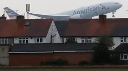 Sebuah pesawat lepas landas melintasi atap rumah di dekat Bandara Heathrow, London, 25 Oktober 2016. Sekitar 1.200 pesawat yang datang dan pergi dari Bandara Heathrow harus melewati kawasan perumahan di Myrtle Avenue. (AP Photo / Frank Augstein)