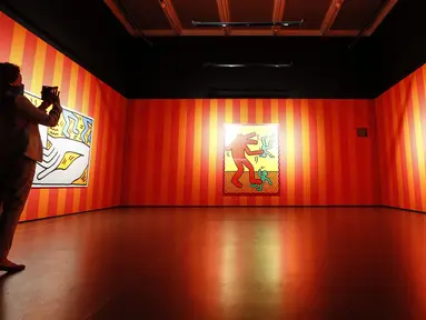 Pengunjung mengamati karya seni seniman Amerika Serikat Keith Haring saat pameran di Museum Folkwang, Essen, Jerman, Selasa(1/9/2020). Keith Haring merupakan seniman jalanan asal New York yang meninggal akibat komplikasi AIDS pada tahun 1990. (AP Photo/Martin Meissner)