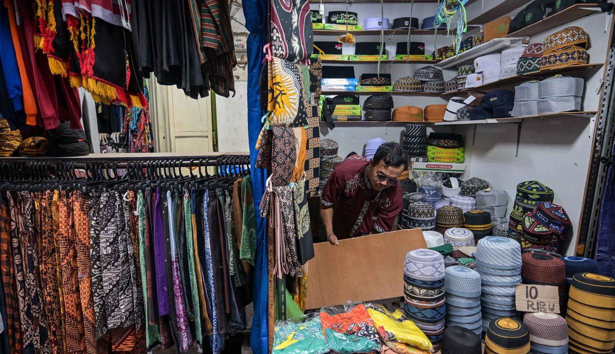 Seorang pedagang menata peci untuk dijual selama bulan suci Ramadan di dekat Masjid Sunan Ampel, Surabaya, Jawa Timur, pada Minggu 8 Maret 2026. Sepanjang Ramadan, kawasan sekitar Masjid Sunan Ampel, Surabaya, Jawa Timur, berubah menjadi pusat belanja dan kuliner yang kental dengan nuansa Timur Tengah. (JUNI KRISWANTO/AFP)