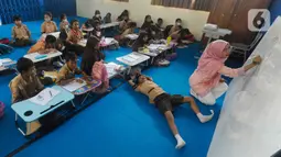 Seorang guru mengajar murid tanpa menggunakan meja dan kursi sekolah, di SDN Bojong Nangka 02, Kabupaten Bogor, Jawa Barat, Kamis (16/2/2023). Sudah lebih dari dua pekan, murid-murid di tiga ruang kelas  menerapkan kegiatan belajar mengajar beralas karpet karena belum tersedianya bangku dan meja. (merdeka.com/Arie Basuki)