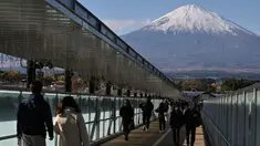 Foto yang diambil pada tanggal 28 November 2024 ini menunjukkan orang-orang berjalan di sepanjang jembatan yang menghubungkan toko-toko di pusat perbelanjaan populer dengan latar belakang Gunung Fuji di kota Gotemba, prefektur Shizuoka, sekitar 100 km di sebelah barat daya Tokyo. (Richard A. Brooks/AFP)