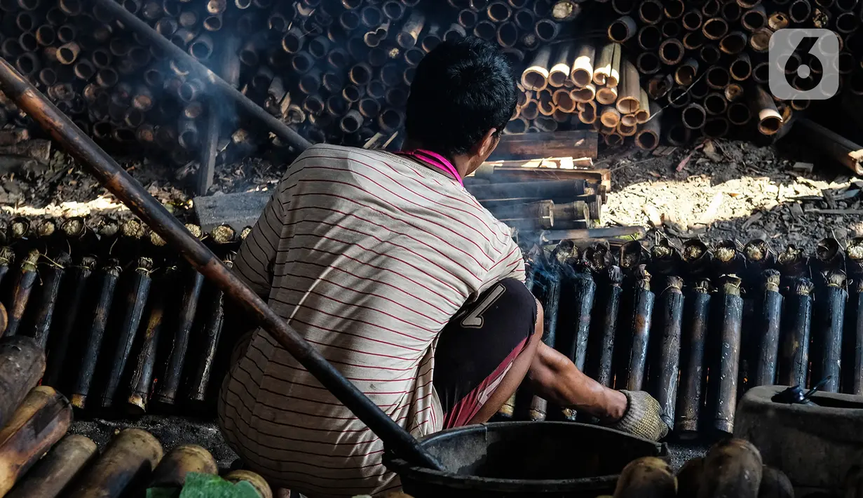 Pekerja membakar lemang yang sudah dibungkus daun pisang dan dimasukkan ke dalam bambu di industri pembuatan lemang kawasan Senen, Jakarta, Selasa (27/4/2021). Lemang merupakan makanan yang berbahan dasar beras ketan. Penganan itu dibuat dengan cara dibakar. (Liputan6.com/Johan Tallo)