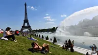 Warga berjemur di samping air mancur di Trocadero Esplanade, dekat Menara Eiffel, Paris (8/5). Kebun Trocadero Esplanade memiliki luas 93.930 meter persegi (23,21 hektar). (AFP Photo/Gerard Julien)