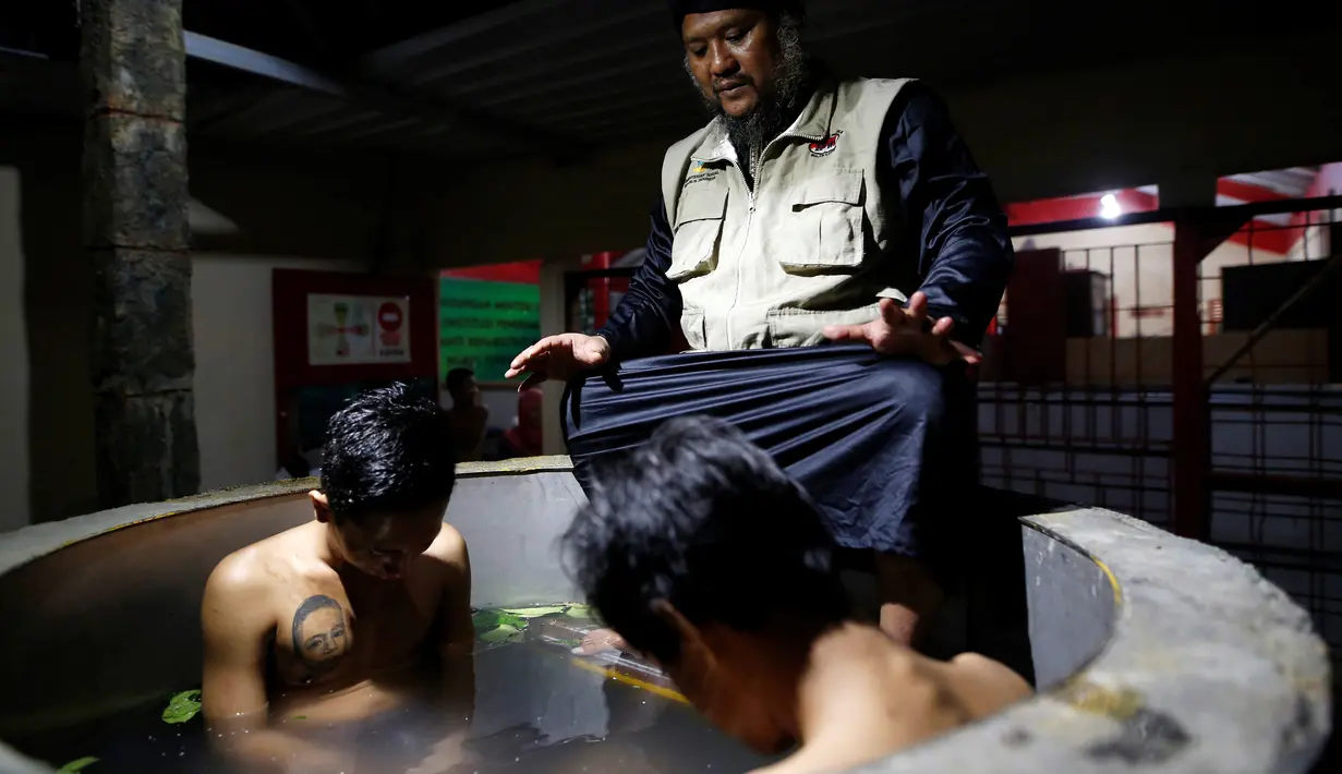 Ustad Ahmad Ischsan Maulana mengobati dua pasien yang berendam dalam bak berisi ramuan herbal di Purbalingga, Jateng, 27 Juli 2016. Terapi untuk pecandu narkoba ini dilakukan dengan merebus pasien di atas kompor yang menyala. (REUTERS/Darren Whiteside)