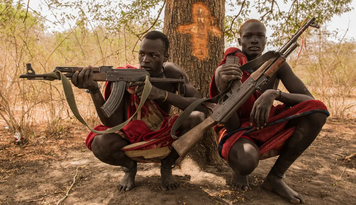 Penggembala dari suku Dinka Makal Maker (kanan) dan Achiek Butich memegang senjata untuk menjaga hewan ternak mereka di Mingkaman, Lakes State, Sudan Selatan, Minggu (4/3). (Stefanie GLINSKI/AFP)