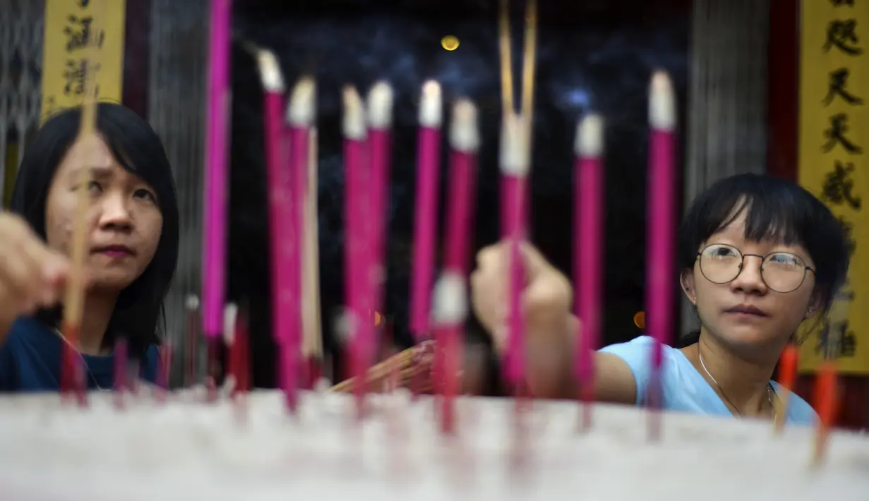 Dua wanita meletakkan dupa di sebuah kuil China menjelang Tahun Baru Imlek di Banda Aceh (19/1/2020). Tahun Baru Imlek jatuh pada 25 Januari tahun ini dan menandai Tahun Tikus. (AFP Photo/Chaideer Mahyuddin)