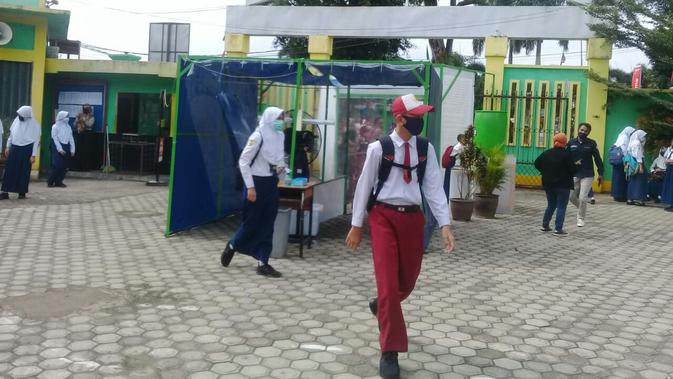 Sejumlah anak sekolah di SMPN 1 Kota Jambi mulai masuk sekolah pertama saat masa pandemi, Senin (13/7/2020). Meski status Kota Jambi zona kuning, Pemkot Jambi telah mengizinkan belajar mengajar tatap muka. (Liputan6.com / Gresi Plasmanto)