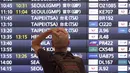 Salah satu wisatawan asing berdiri di depan papan informasi penerbangan setibanya di Bandara Internasional Haneda, Tokyo, Selasa (11/10/2022).  Langkah Jepang untuk menghapus sebagian besar pembatasan pada turis asing akhirnya mulai diterapkan ketika gelombang pandemi paling mematikan di negara itu surut. (AP Photo/Eugene Hoshiko)