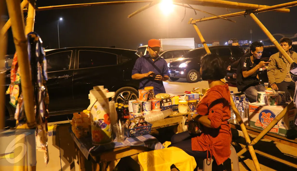 Seorang pemudik membeli makanan ringan yang dijajakan pedagang di pinggir Tol Cikopo, Jawa Barat, Jumat (1/7). Para pedagang dadakan yang menjajakan aneka makanan ringan dan minuman mulai menjamur di sepanjang jalur tersebut. (Liputan6.com/Angga Yuniar)