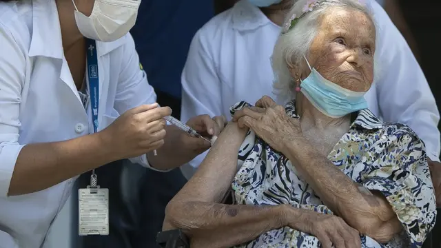 Zelia de Carvalho Morley, nenek berusia 106 tahun penyintas Flu Spanyol menerima suntikan vaksin COVID-19 CoronaVac, buatan Sinovac, di Rio de Janeiro, Brazil (20/1/2021). (Photo credit: AP Photo/Bruna Prado)